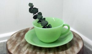 a jadeite tea cup and saucer on a wooden stand
