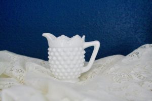 white hobnail creamer displayed on a lace cloth