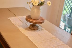 a vintage table embroidered table runner with an enamelware vase