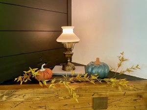 fall decor on a mantel with pumpkins