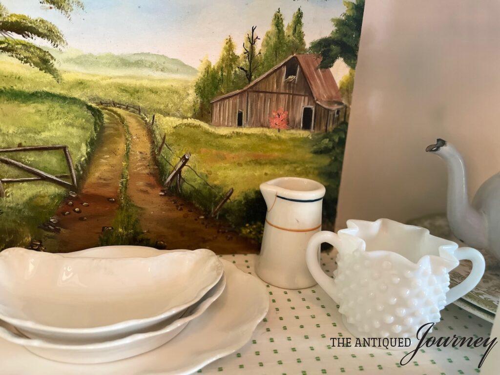 a vintage scene of milk glass and creamers in a hutch