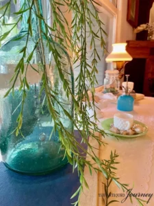 a thrifted glass jug with faux greenery as a vase