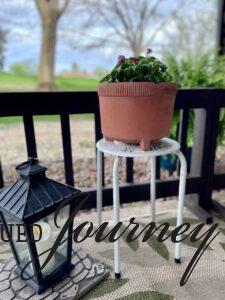 a flower pot sitting on a metal plant stand