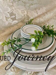 vintage green and white dishes stacked with faux flowers