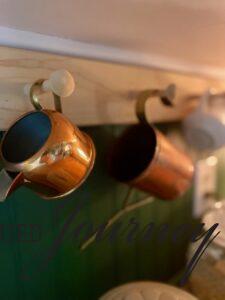 vintage copper creamers hanging on a peg rack