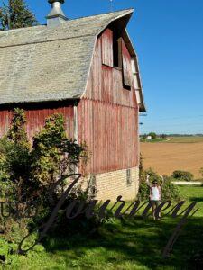 standing next to giant red barn