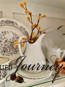 a vintage ironstone pitcher used for fall decorating in a hutch