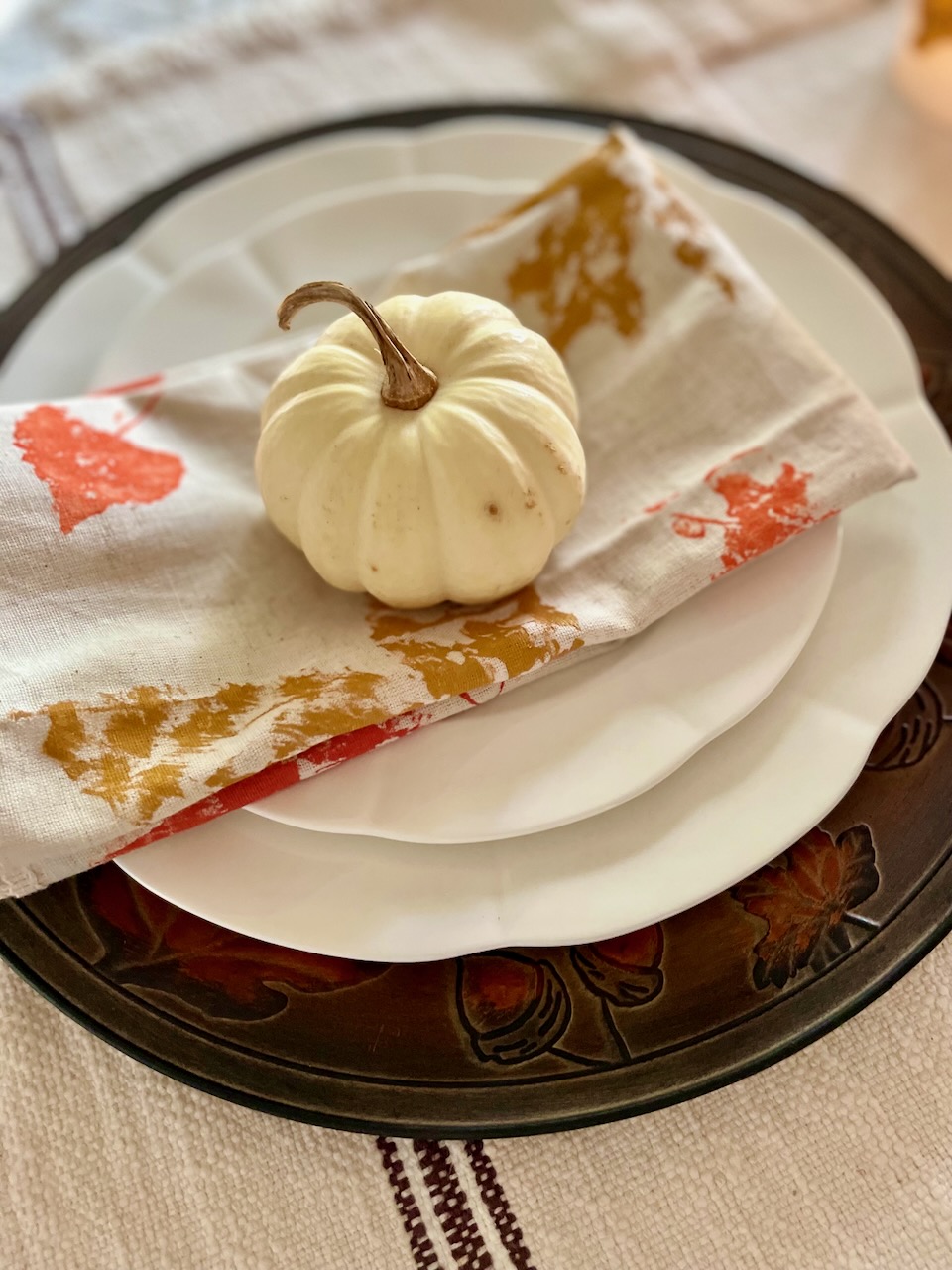 a DIY leaf stamped napkin for fall with a white pumpkin on top