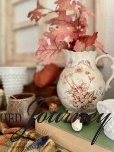 a vintage fall decor shelf with ironstone and thrifted finds