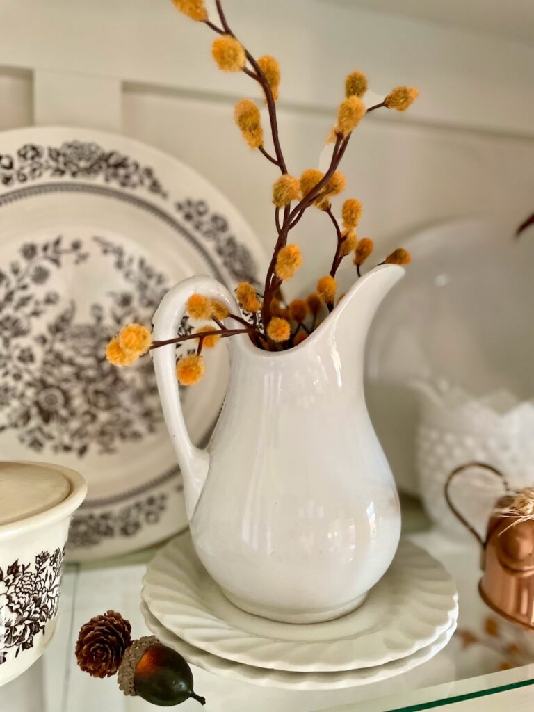 a vintage ironstone pitcher styled in a hutch for thrifty Thanksgiving decor