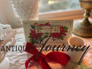 an antique Christmas postcard tucked into a vignette with red velvet ribbon