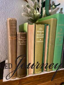 a row of vintage green books styled on a mantel for sustainable Christmas decor