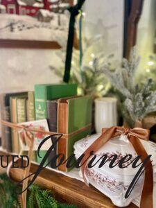 a row of vintage green books tied with a gold bow and a vintage Christmas postcard styled on a mantel for Scandinavian Christmas decor