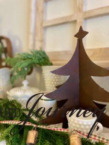 a vintage brass Christmas tree on a shelf with greenery and other pieces of vintage decor