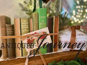 a collection of vintage green books lined up across a mantel tied with a ribbon for Nordic inspired Christmas decor