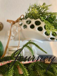 a milk glass banana stand styled with faux cedar stems for a Christmas display 