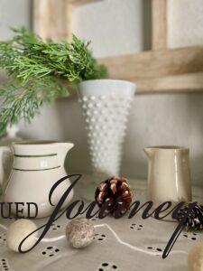 a milk glass vase used for winter decorating with greenery stems