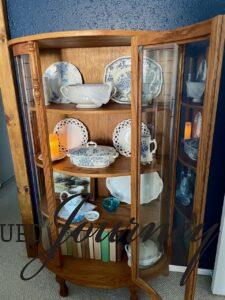an antique curved glass cabinet decorated with thrifted and vintage decor for a display