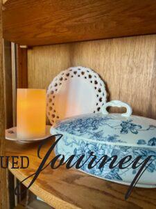 a faux pillar candle used for ambient lighting inside an antique curio cabinet