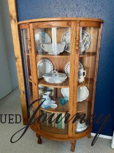 an antique, thrifted curio cabinet decorated with vintage finds