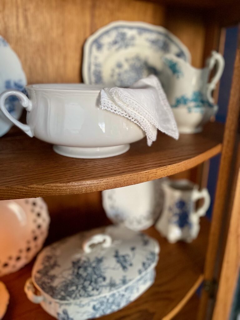 vintage blue and white decor styled in a curved glass curio cabinet
