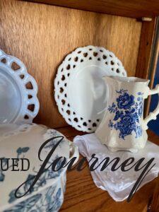 a vintage hanky styled with blue and white transferware in a small curio cabinet