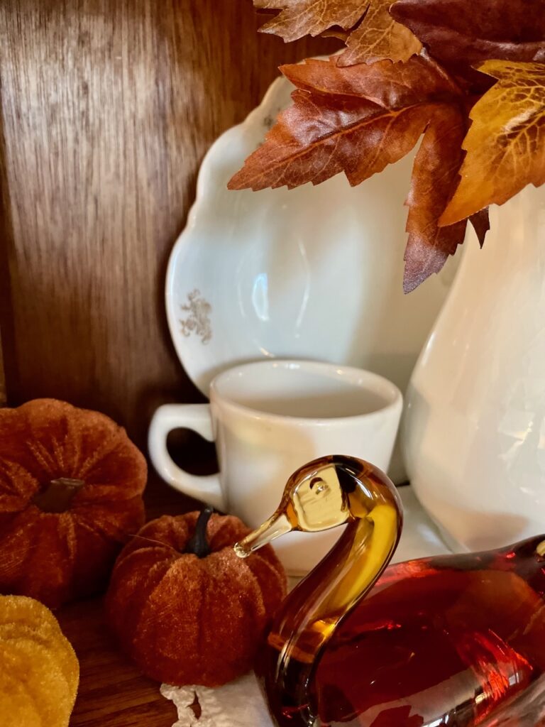 thrifted fall decor styled in an antique curio cabinet