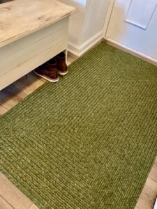 a braided green rug in a small entryway