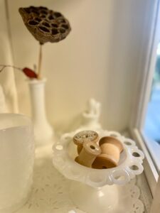milk glass styled with vintage thread spools for thrifted home decor