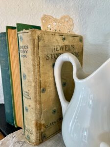 a vintage lace doily styled with a vintage book on a mantel vignette