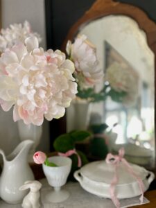 pink peony flowers styled in a milk glass vase along side vintage decor on a mantel for spring