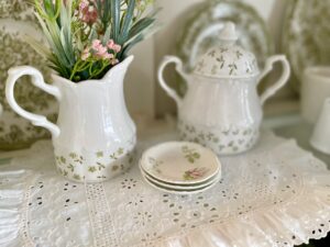 spring hutch vignette with ironstone, vintage linens, faux florals, and thrifted art on a budget