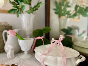Vintage spring mantel decor featuring large faux peonies in a milk glass vase 