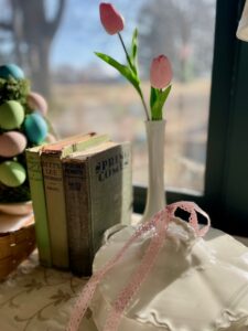 Thrifted spring decor on a credenza featuring a woven basket, ironstone, and antique books