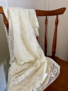 a vintage tablecloth styled on a wooden chair 