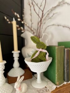 a floral arrangement with pussy willows styled with vintage decor on a spring mantel