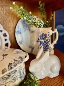 blue and white vintage dishes and linens arranged in a glass door curio cabinet for spring
