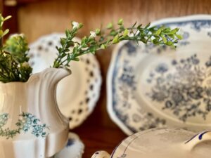 blue and white vintage dishes and linens arranged in a glass door curio cabinet for spring
