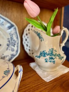middle shelf of a glass curio cabinet decorated with blue and white spring vignette