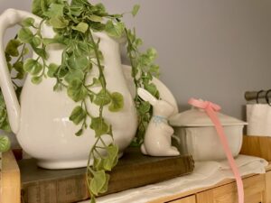 Faux greenery styled alongside vintage decor in a bathroom vignette