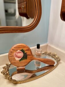 Mirrored vanity tray corralling vintage pieces on a bathroom surface