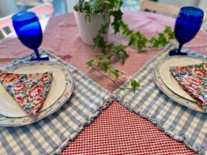vintage linen tablescape with floral tablecloth and cloth napkins at place settings paired with vintage dishes