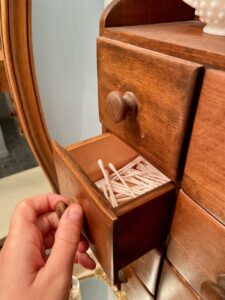 Vintage spice cabinet with small drawers used for bathroom storage in a styled space