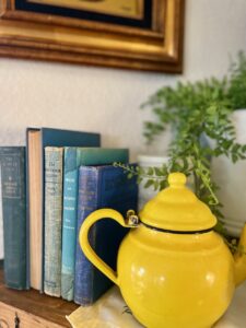 Vintage books stacked and layered beneath enamelware on a charming summer mantel