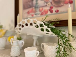 milk glass collection decorated for summer on a wall shelf with yellow accents