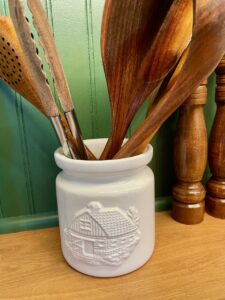 a vintage thrifted crock used to hold cooking utensils in a kitchen