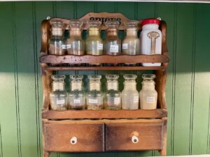 a vintage spice rack hanging on a kitchen wall