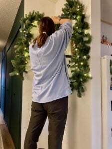 hanging a King of Christmas pre-let Fir garland in an entryway